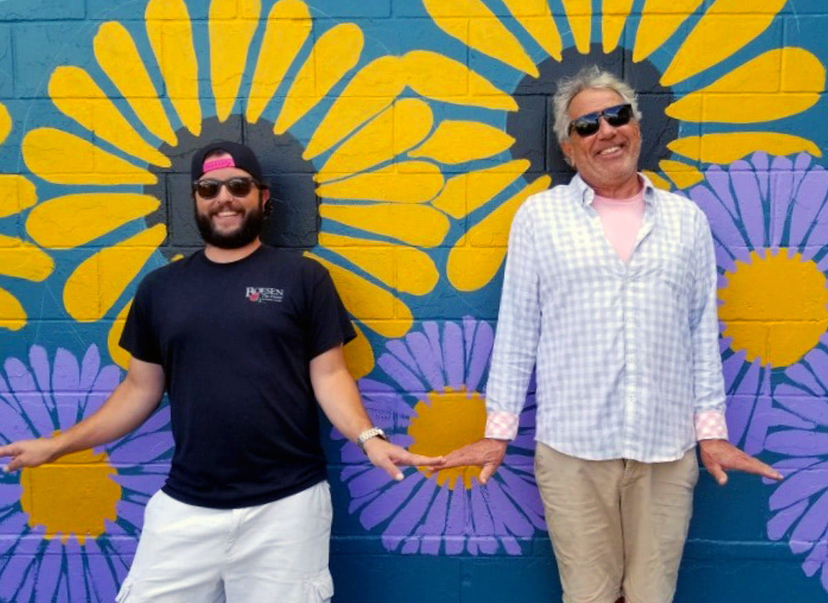 A pair of Boesen's owners clowning around near a floral-themed mural